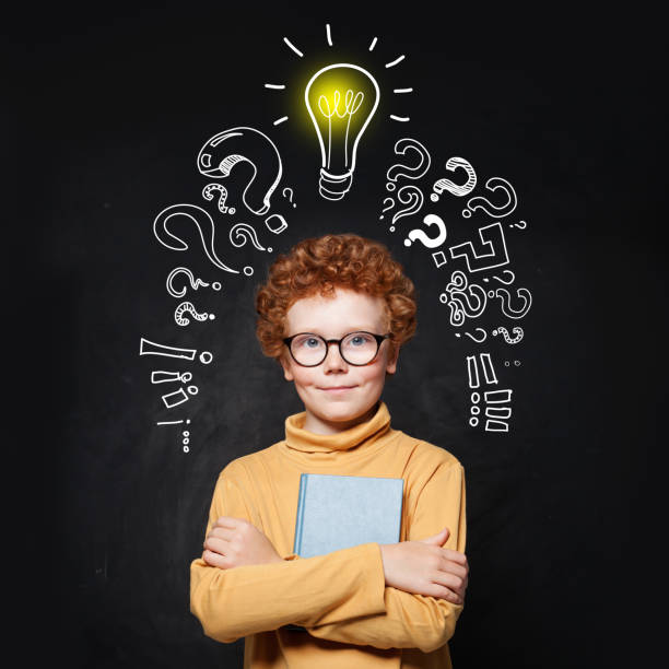istock Pupil boy looking at camera on chalkboard background with lightbulb 1192369508