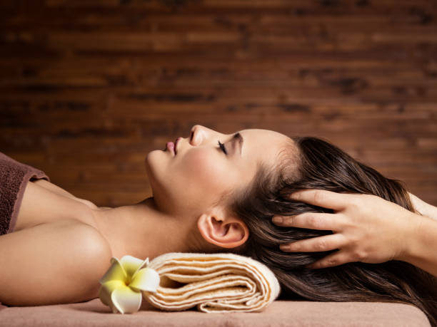 Masseur doing massage the head and hair for an woman in spa salon stock photo