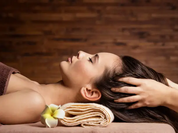 Photo of Masseur doing massage the head and hair for an woman in spa salon