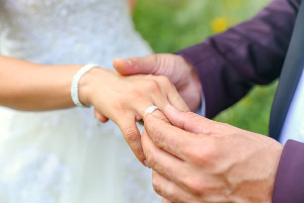 istock groom's hand putting a wedding ring on the bride's finger. Wedding ceremony. 1192377131
