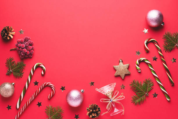 istock Christmas baubles, golden decorations, candy canes, pine tree, cones and confetti frame on red background. Festive Christmas border with golden elements. Flat lay, top view, copy space 1192381502