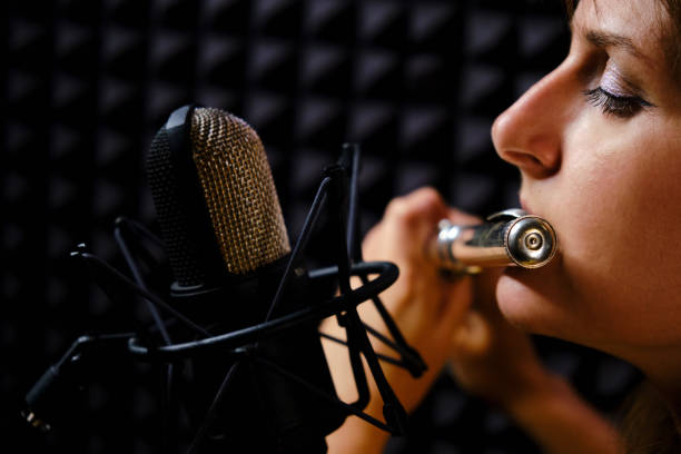 la flûte de fille dans le joueur d'écouteur joue dans le studio d'enregistrement, plan rapproché. enregistrez des instruments de musique à vent avec un microphone professionnel. flûtiste de femme jouant la flûte de concert, fond noir. - flûte traversière photos et images de collection