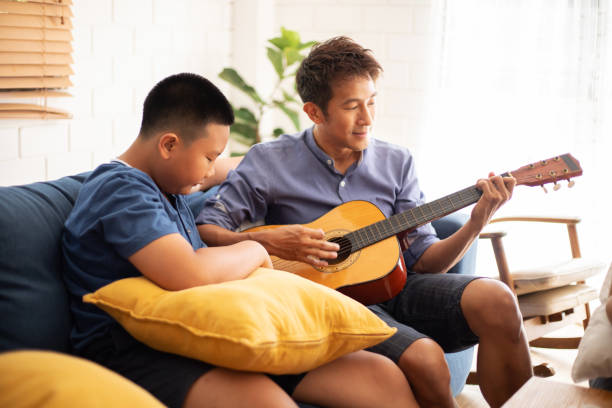 Father playing guitar with boy with smile happy in home. Father playing guitar with boy with smile happy in home. father and son guitar stock pictures, royalty-free photos & images