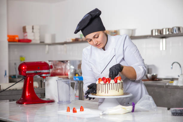 female baker preparing strawberry age cake stock photo