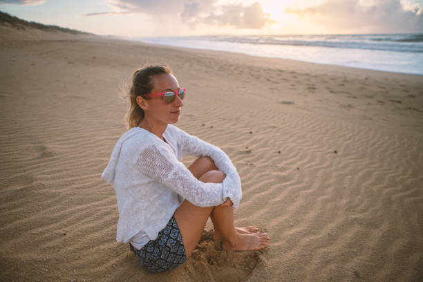istock Young woman contemplating sunset on beach 1192399127