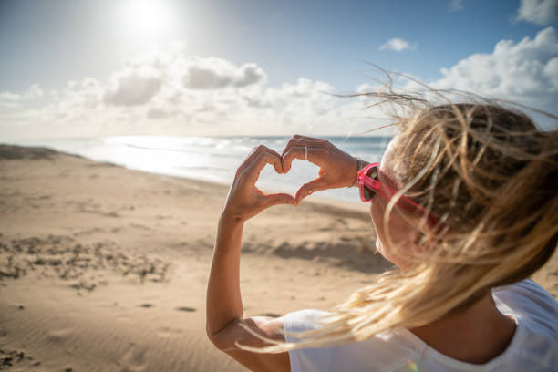 Girl loving each at sunset making heart with hands