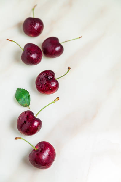 istock Juicy wet red cherries on white marble tab table, top view, vertical composition 1192403720