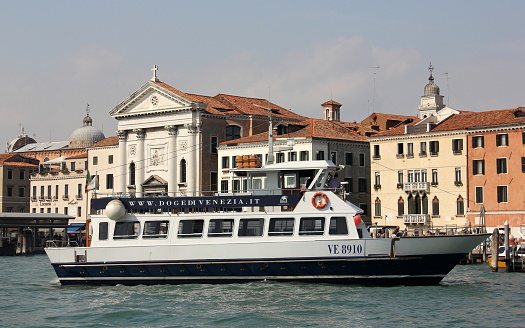 Tourist charter boat at the waterfront with  the Church of the Pieta - Saint Mary of the Visitation in the background, Venice, Italy