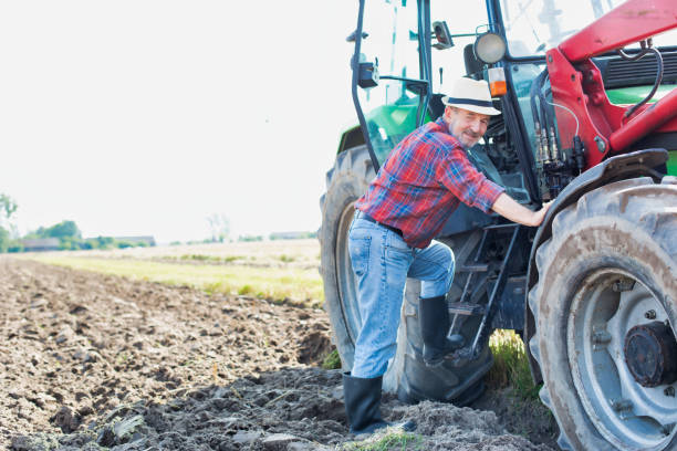 istock Senior farmer hopping on tractor in field 1192420371