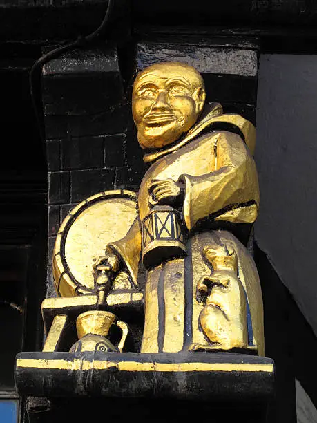 Medieval wooden exterior detail from an old traditional pub in London's Fleet Street showing a Benedictine monk filling a jug of ale