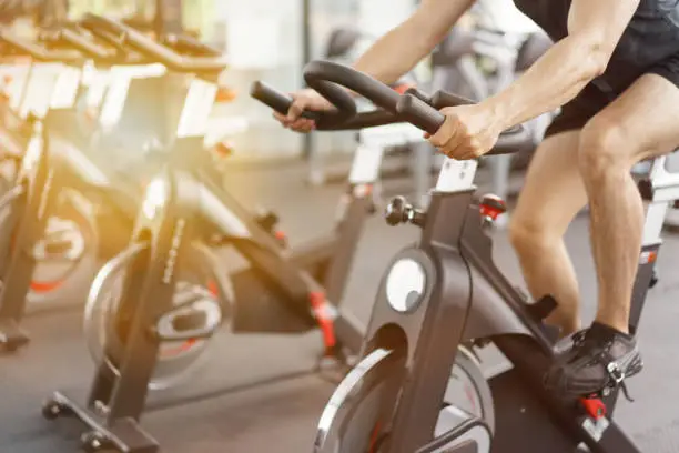 Photo of Asian man cycling on bike in fitness gym.