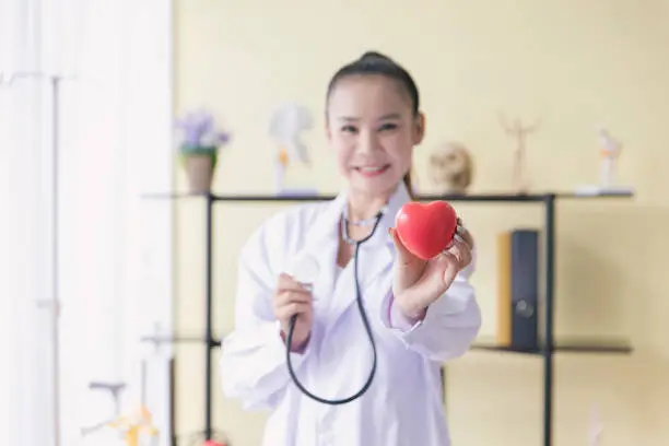Photo of Young woman asian doctor holding a red heart