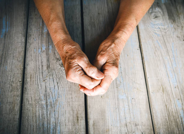 Senior woman with fingers crossed. Wrinkled palms stretched forward. Religion, take care, mothers day, warmth concept. Human emotions, old people health, love and compassion.