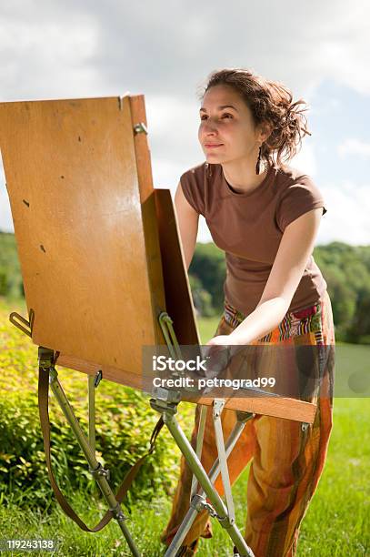 Young Woman Looking At A Painting Easel Outside In A Field Stock Photo - Download Image Now