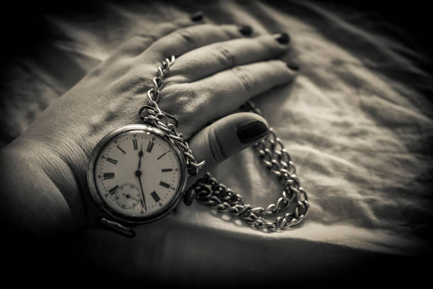 A black and white photo of a woman's hand holding a retro pocket watch