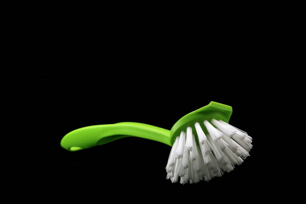 Green dishwashing brush isolated on black background.