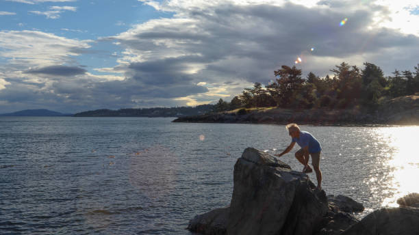 istock Mature man scrambles up rocks on beach at sunrise 1192446926