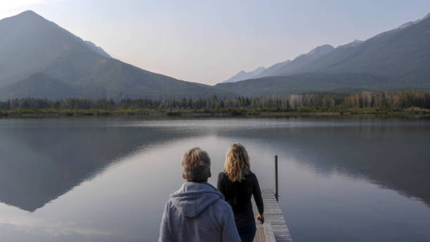 They look off to distant scene of mountains reflecting in water