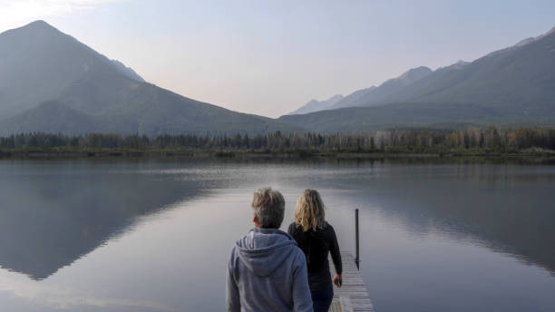 They look off to distant scene of mountains reflecting in water