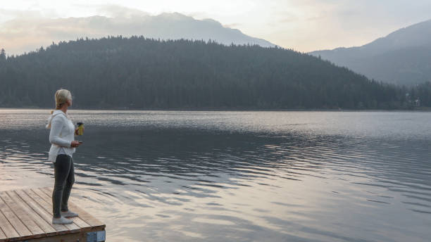istock Mature woman relaxes by lake while sipping on hot beverage 1192448367