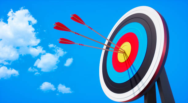 Archery target and arrow on blue sky Archery target with hits by several arrows with sun against a clear blue sky with little clouds bulls eye stock pictures, royalty-free photos & images
