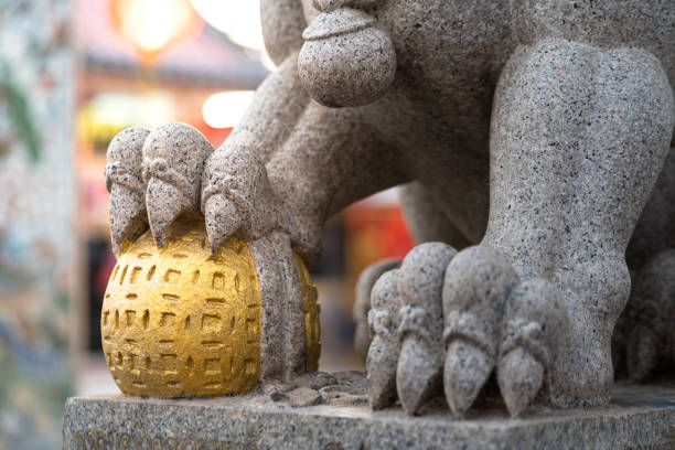 A Chinese traditional lion statue which is standing in front of temple gate. The statue is represented as powerful guardian, as culture believing.