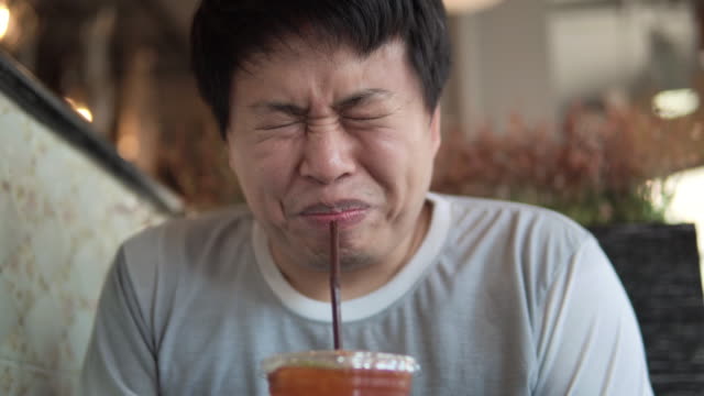 Asian man makes faces grimacing when eating lemon tea.
