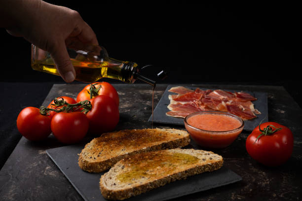 aceite de efusión a mano en tostadas con jamón y tomate. desayuno mediterráneo, cocina española - alimento tostado fotos fotografías e imágenes de stock