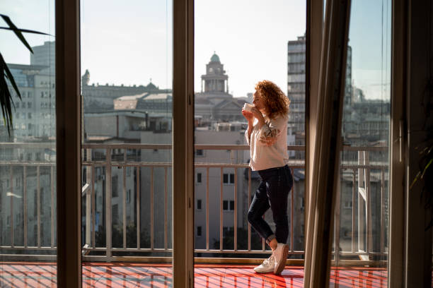 istock Young woman drinking coffee on balcony and enjoying the view 1192466247