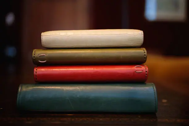 Photo of Stack of leather diaries on an old wooden desk.