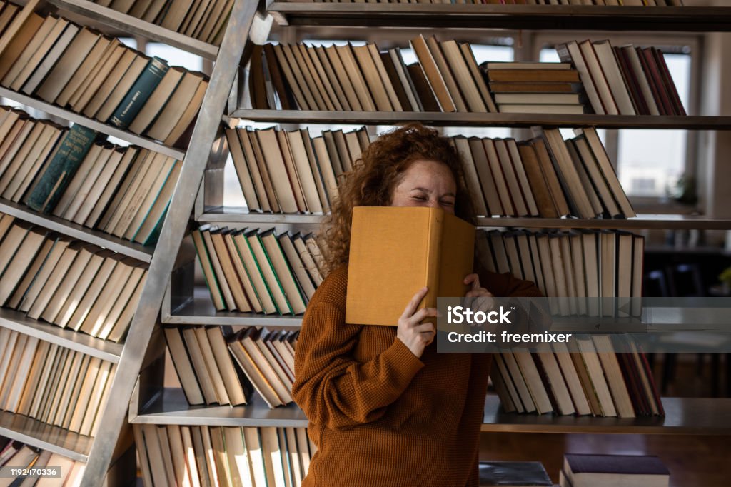 Young woman reading a book in apartment Book Stock Photo