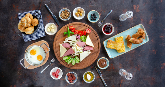 Turkish breakfast, eggs, olives, honey with butter, Turkish bagel, cheese and bread on metallic background. Top view