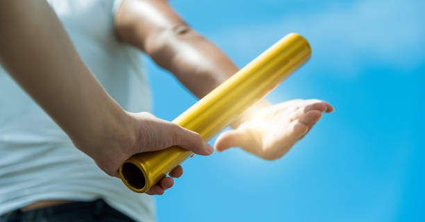 istock Two hands passing the baton for a relay race 1192473968