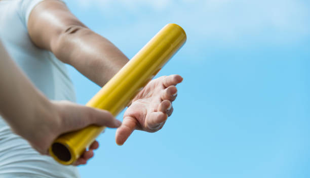 istock Two hands passing the baton for a relay race 1192474155