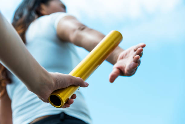 istock Two hands passing the baton for a relay race 1192474157