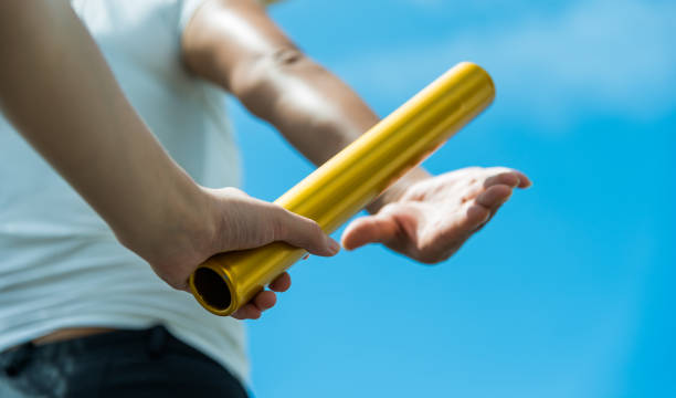 istock Two hands passing the baton for a relay race 1192475011