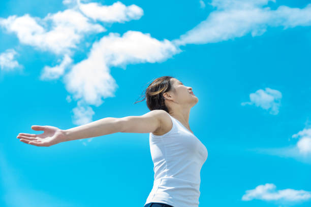 Young woman with hands stretched against sky.