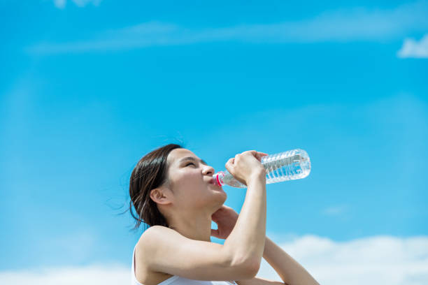 istock Young woman drinking water against sky 1192475389