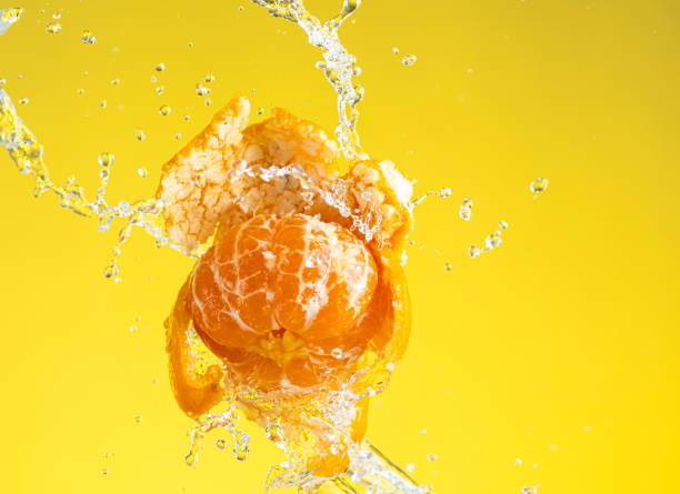 tangerine is almost peeled with a spray of water hanging