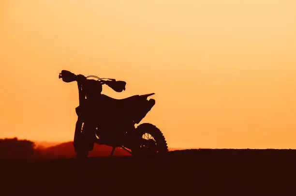 Dark silhouette of a motocycle on sunset light