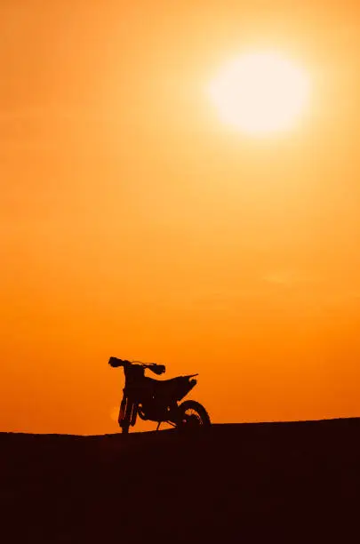 Dark silhouette of a motobike and the sun in the evening.