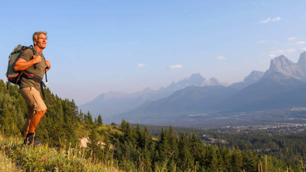 istock Mature man hikes along mountain ridge at sunrise 1192480154