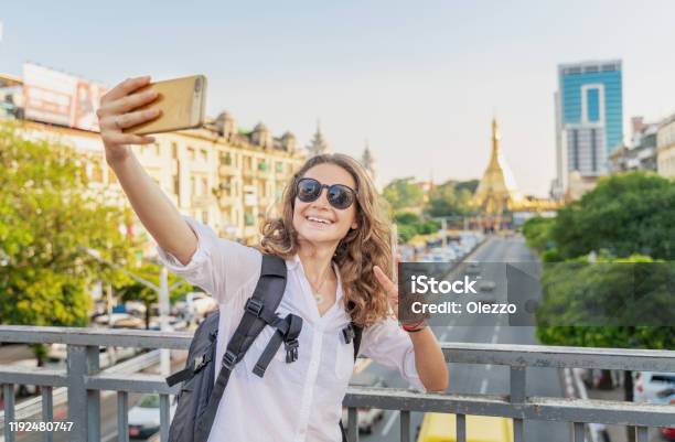 Young Happy Curly European Girl Traveler Takes A Selfie On The Background Of Yangon The Capital Of Myanmar At Sule Pagoda Stock Photo - Download Image Now