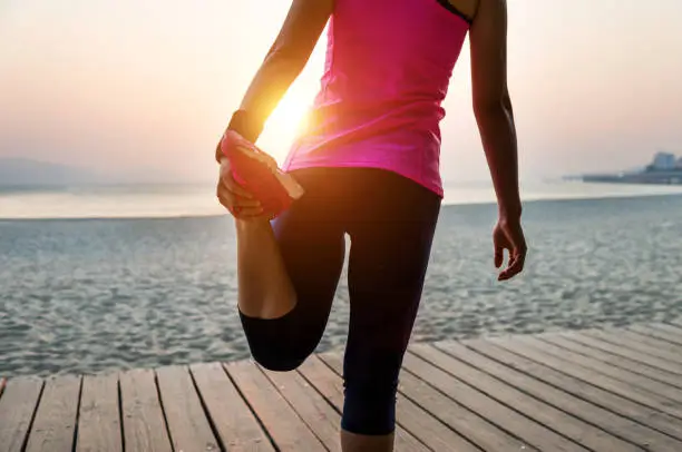 Photo of Female runner stretching before run at beach