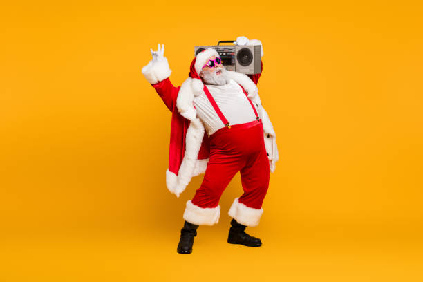 foto de longitud completa de divertido santa claus hipster con gran vientre hold boombox divertirse escuchar villancicos de navidad celebrar x-mas noel fiesta usar sombrero rojo botas de sombrero aislado color amarillo fondo - retro christmas audio fotografías e imágenes de stock