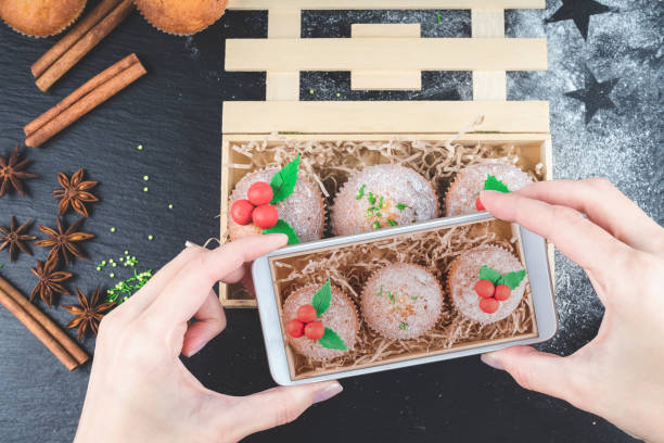 cellulare che spara cupcake natalizi decorati con vischio in una scatola di legno. scattare foto di mini muffin. cibo dolce natalizio. - muffin blueberry muffin blueberry food foto e immagini stock
