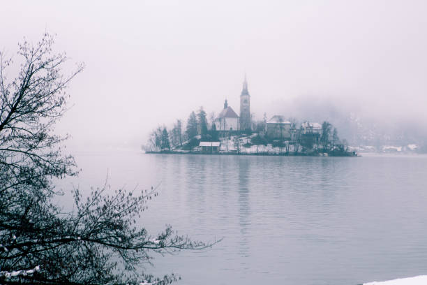 invierno en el lago desangrado. iglesia en la isla - castle slovenia winter snow fotografías e imágenes de stock