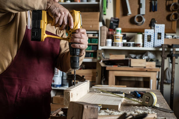 istock Carpenter with a yellow drill making a hole with a wooden drill on board 1192496786