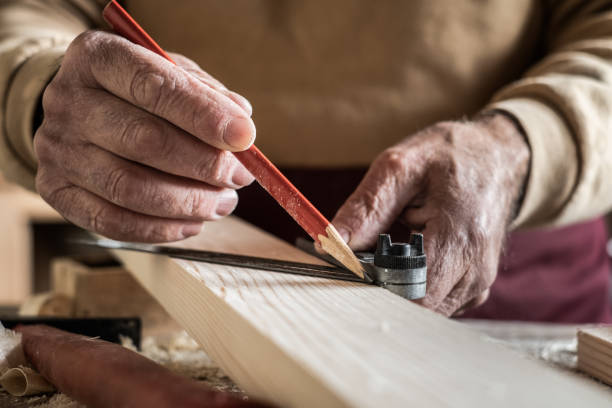 istock Carpenter measuring a plank with a red pencil and a metal ruler 1192496803