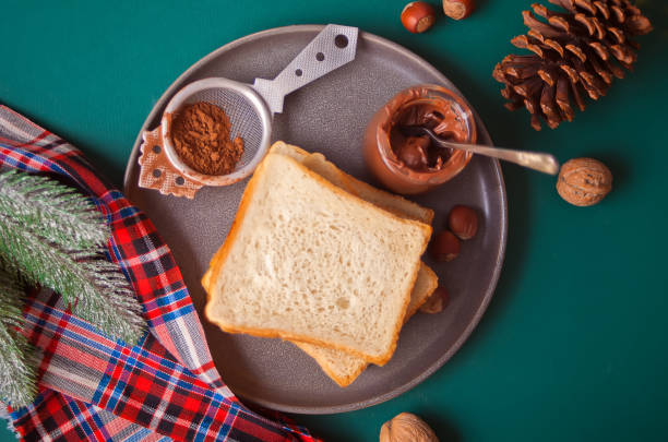 Bread toast with chocolate cream butter on the green background with Christmas decoration.
